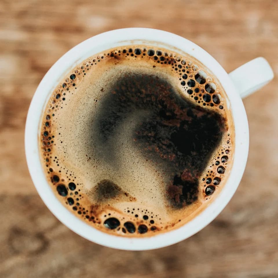 A white cup filled with coffee on a wooden table
